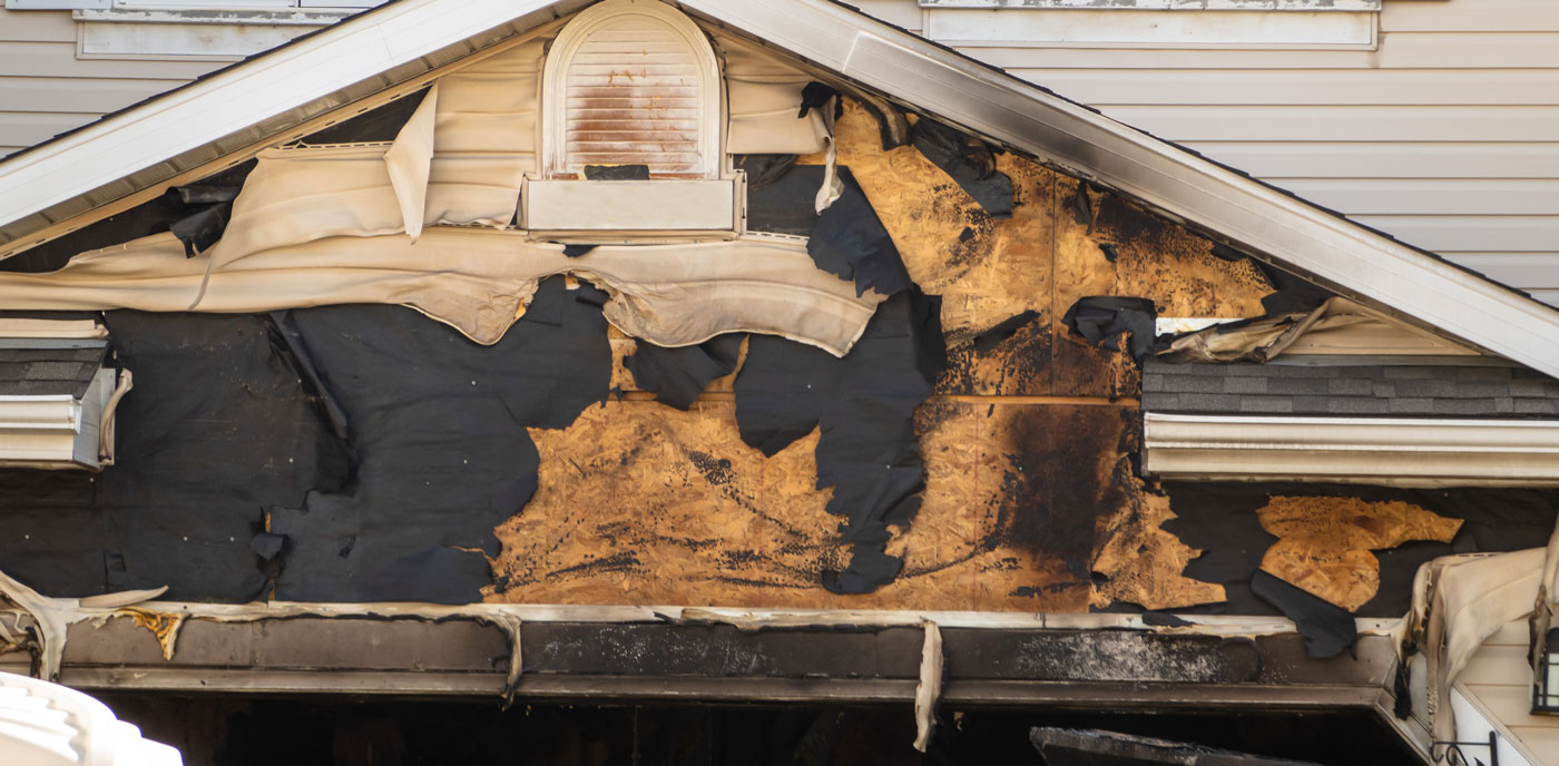 Fire damage in a garage exterior, singed and melted vinyl siding and wood, in Chicago